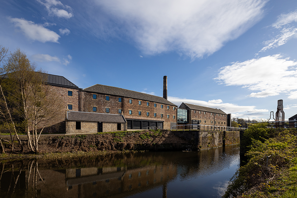 Historic distillery buildings along the canal with restored lockkeepers cottage in the foreground