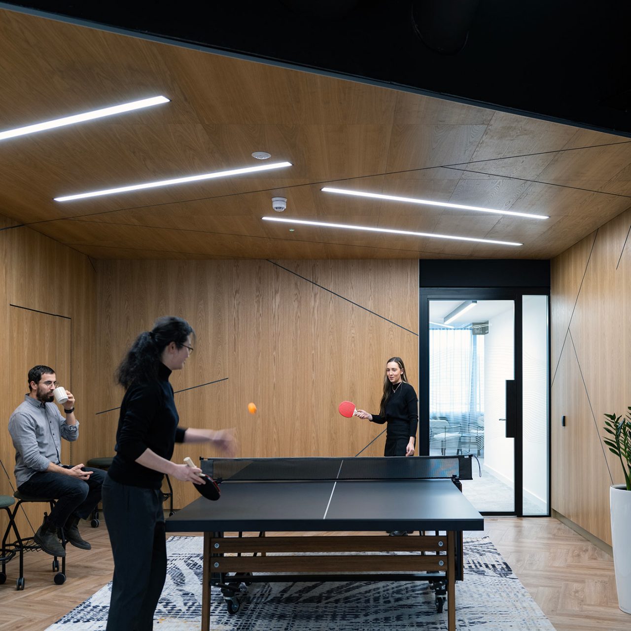 Two women playing ping pong on a black table