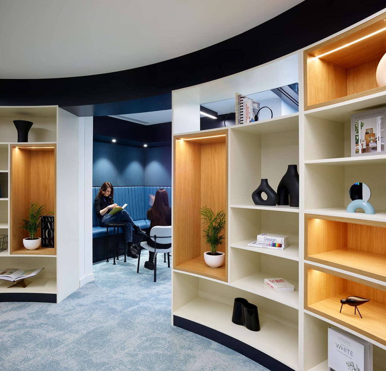 Shelving units with objets and planting then a nook space in blue with lounge furniture visible in the middle